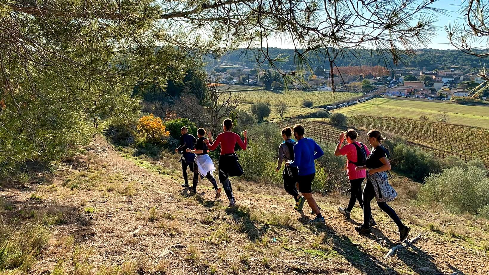 Groupe de marcheurs et de traileurs sur un sentier dominant Aumes, ses vignes et ses garrigues.